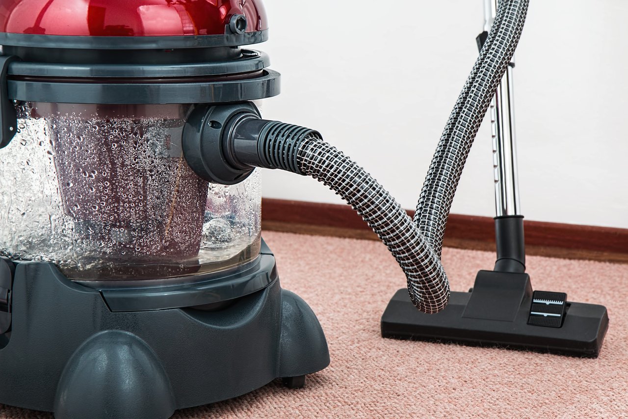 hero-img-01 Close-up of a modern vacuum cleaner with water filtration on carpet floor indoors.